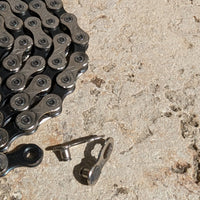 KMC MissingLink 11R CL555R Kettenschloss neben KMC X11 Fahrradkette, Detailaufnahme auf Steinuntergrund