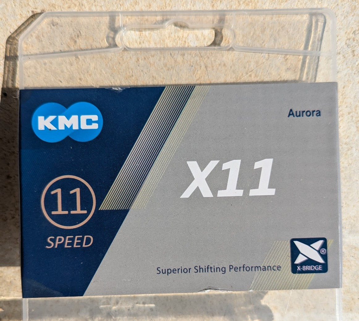 Originalverpackung der KMC X11 Aurora 11-fach Fahrradkette mit Aurora-Farbfinish und X-Bridge Technologie für präzises Schalten