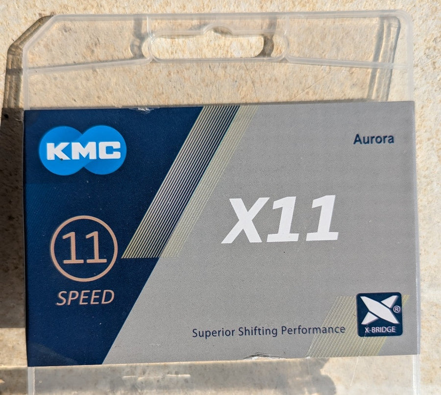 Originalverpackung der KMC X11 Aurora 11-fach Fahrradkette mit Aurora-Farbfinish und X-Bridge Technologie für präzises Schalten