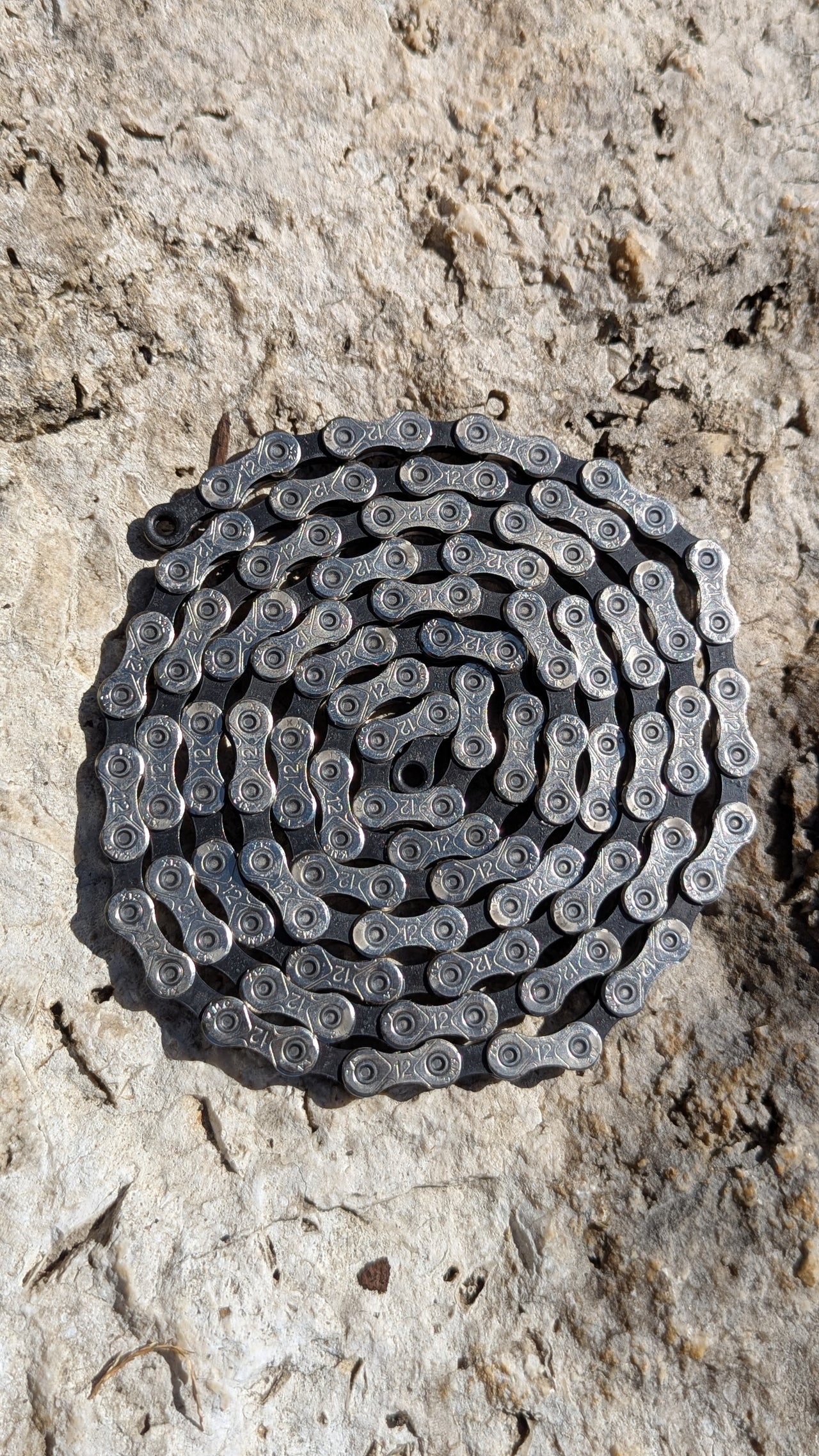 KMC X12 12-fach Fahrradkette mit 126 Gliedern, pre-waxed mit Molten Speed Wax, ausgelegt auf Steinoberfläche
