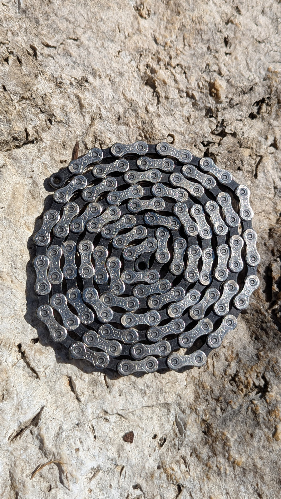 KMC X12 12-fach Fahrradkette mit 126 Gliedern, pre-waxed mit Molten Speed Wax, ausgelegt auf Steinoberfläche
