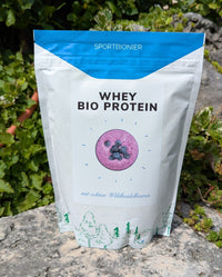Bio Molkenprotein Wildheidelbeere von Sportbionier im Garten fotografiert – natürliches Proteinpulver mit nur zwei Zutaten