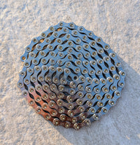 Mit Molten Speed Wax behandelte Cycling Components CN/Twelve SLV 126 TW 12-fach Fahrradkette eingerollt auf hellem Untergrund